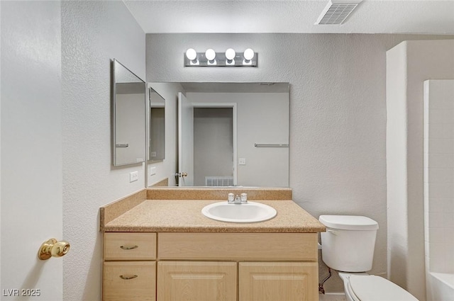 bathroom with visible vents, a textured wall, vanity, and toilet