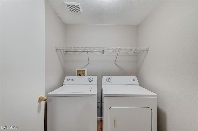 laundry room with a textured ceiling, laundry area, independent washer and dryer, and visible vents