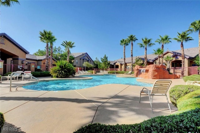 pool with a patio area, fence, and a residential view