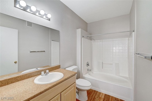 full bath with bathtub / shower combination, toilet, wood finished floors, visible vents, and vanity