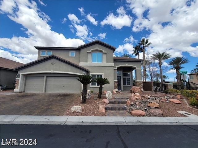 mediterranean / spanish home with decorative driveway, fence, an attached garage, and stucco siding