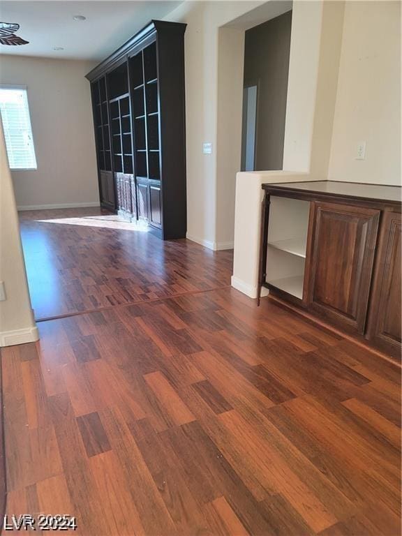 spare room featuring baseboards and dark wood finished floors