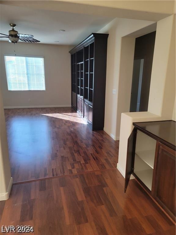 unfurnished room with ceiling fan, dark wood-style flooring, and baseboards