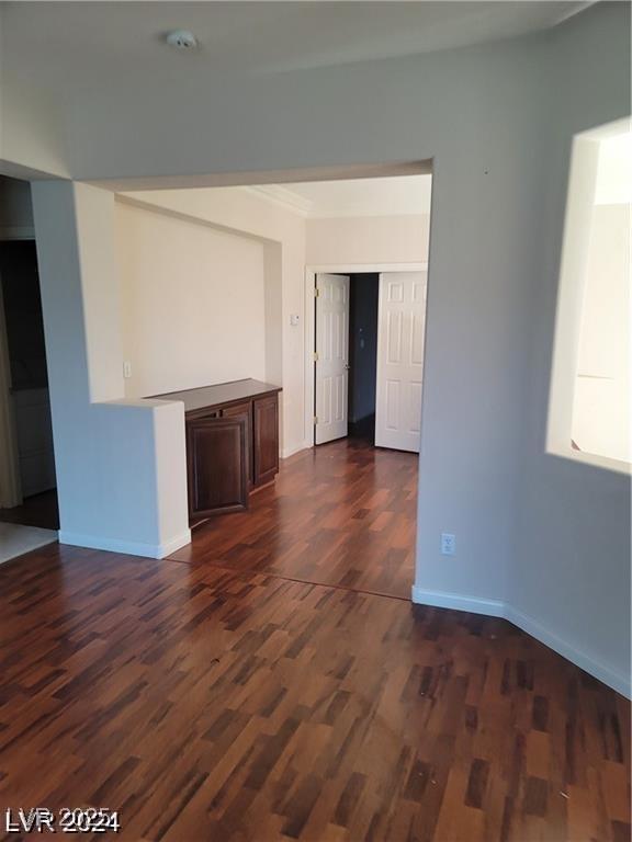 unfurnished room featuring dark wood-type flooring and baseboards