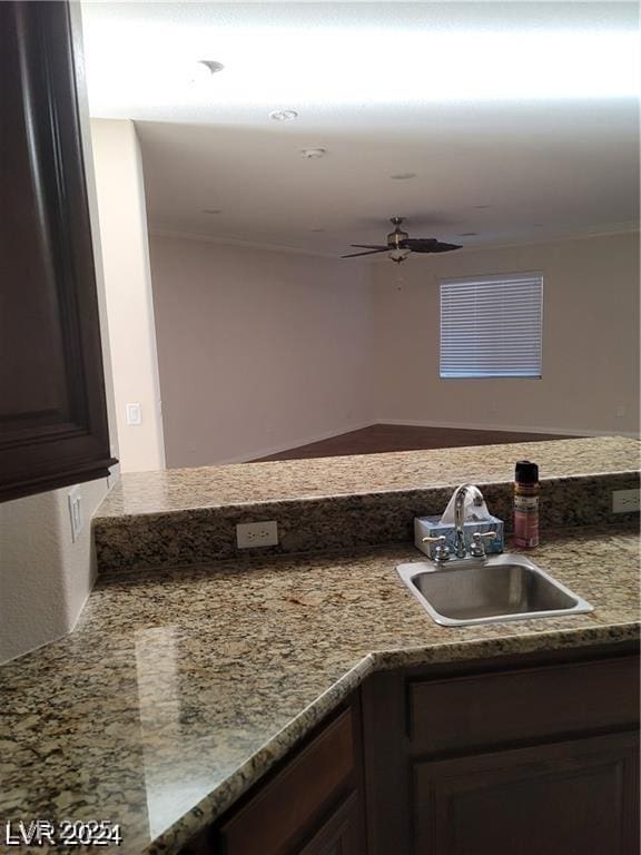 kitchen featuring light countertops, ornamental molding, a sink, and a ceiling fan