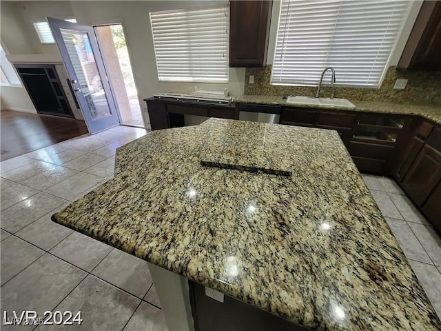 kitchen with light tile patterned floors, tasteful backsplash, light stone counters, and a sink