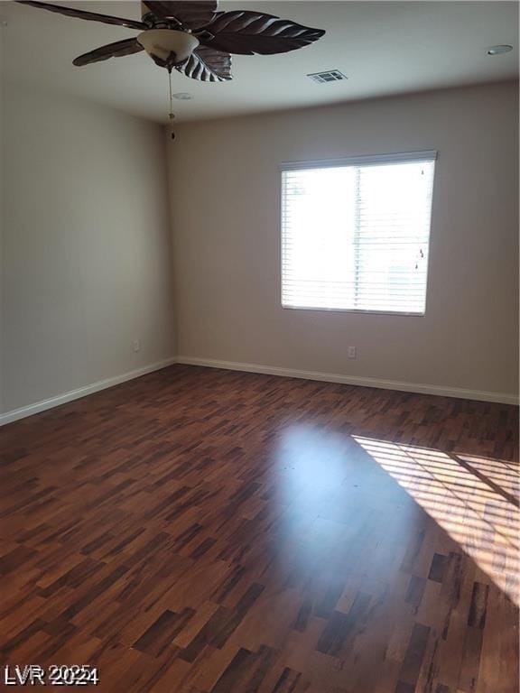 empty room featuring baseboards, visible vents, ceiling fan, and dark wood-style flooring