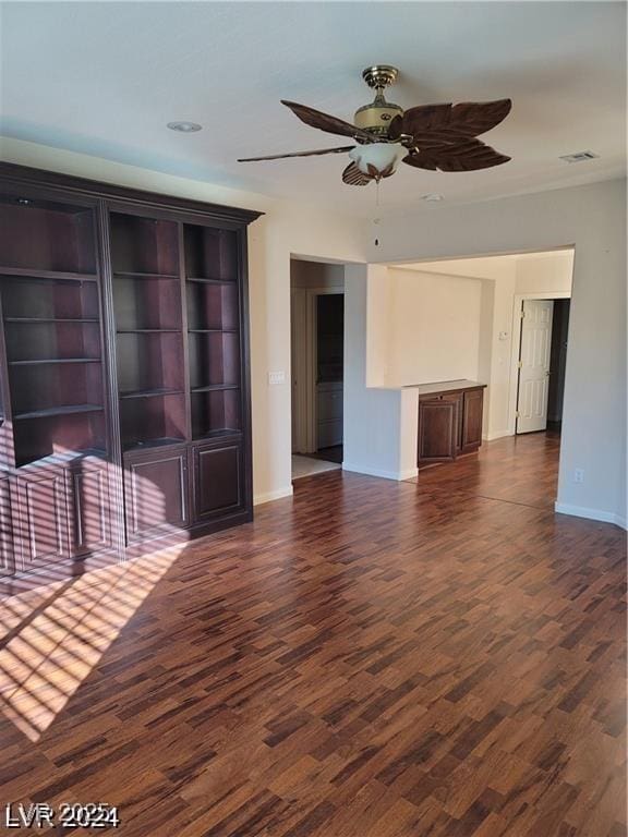 unfurnished living room featuring dark wood-style flooring, visible vents, ceiling fan, and baseboards