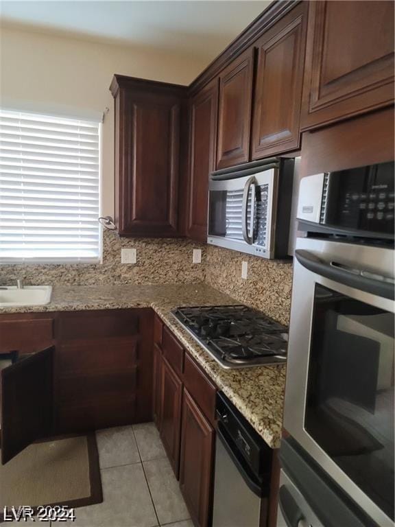 kitchen with light stone countertops, light tile patterned floors, appliances with stainless steel finishes, and backsplash