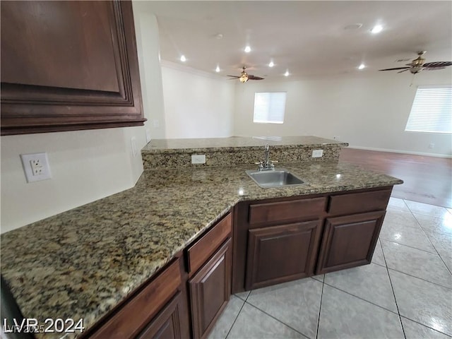 kitchen with a healthy amount of sunlight, light stone counters, a sink, and light tile patterned flooring