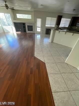 unfurnished living room featuring light tile patterned floors, ceiling fan, and a fireplace