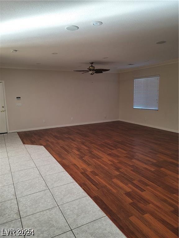 empty room with ceiling fan, ornamental molding, wood finished floors, and baseboards