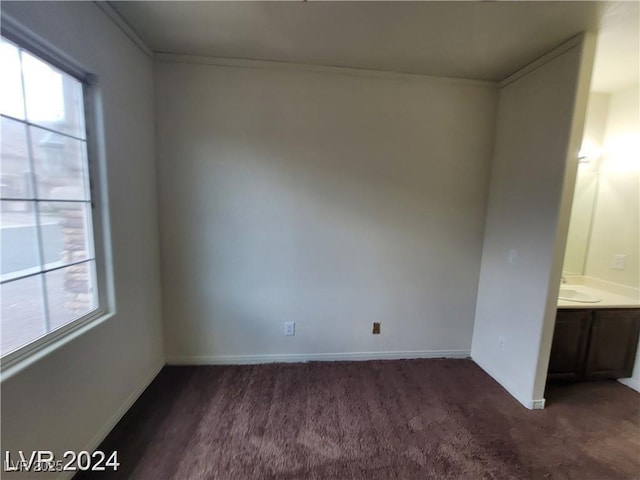 unfurnished bedroom with multiple windows, dark carpet, and baseboards