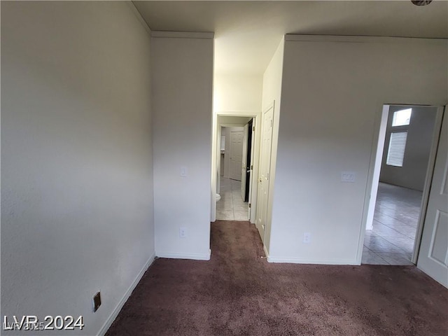 unfurnished room with dark colored carpet and baseboards