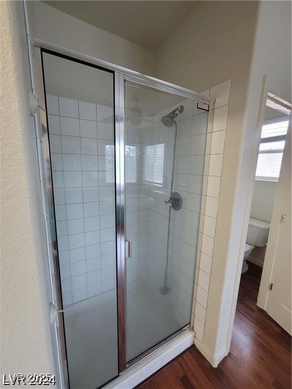 full bathroom featuring wood finished floors, toilet, and a shower stall