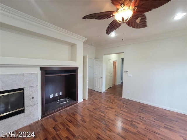 unfurnished living room with a tiled fireplace, ornamental molding, a ceiling fan, wood finished floors, and baseboards