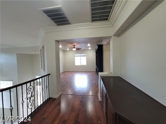 corridor with dark wood-style flooring, visible vents, crown molding, and baseboards