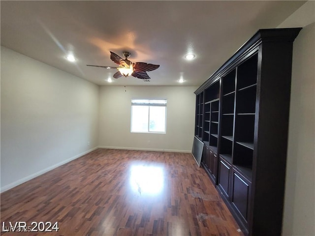 empty room with a ceiling fan, baseboards, and dark wood-style flooring