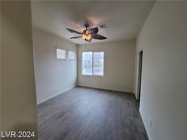 unfurnished room featuring dark wood-style floors, ceiling fan, visible vents, and baseboards