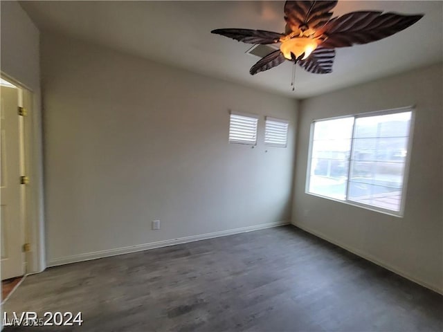 spare room featuring dark wood-style flooring, plenty of natural light, and baseboards