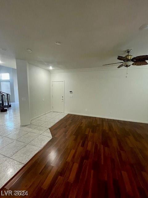 unfurnished room with ornamental molding, light wood-type flooring, a ceiling fan, and baseboards