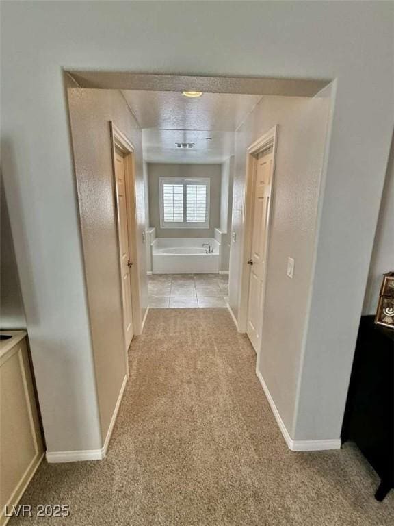 corridor featuring light carpet and baseboards