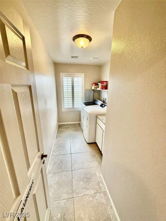 washroom featuring cabinet space, light tile patterned floors, baseboards, and a textured wall