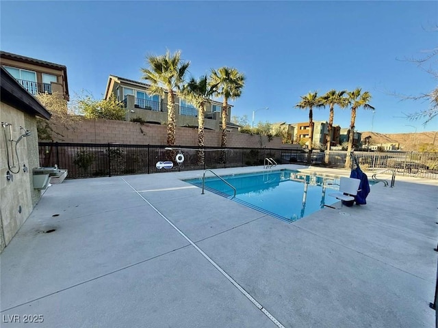 pool with a patio area and fence