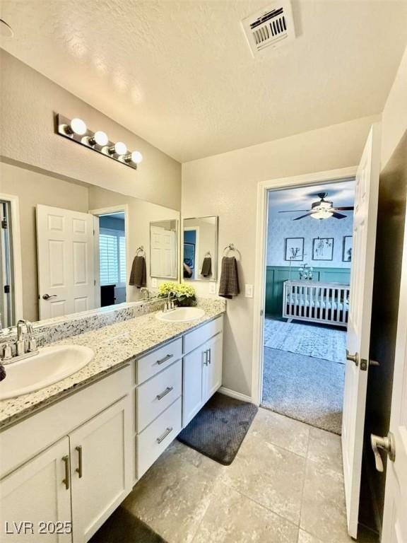 bathroom featuring double vanity, a textured ceiling, visible vents, and a sink