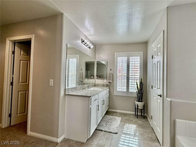 bathroom featuring a textured ceiling, vanity, and baseboards