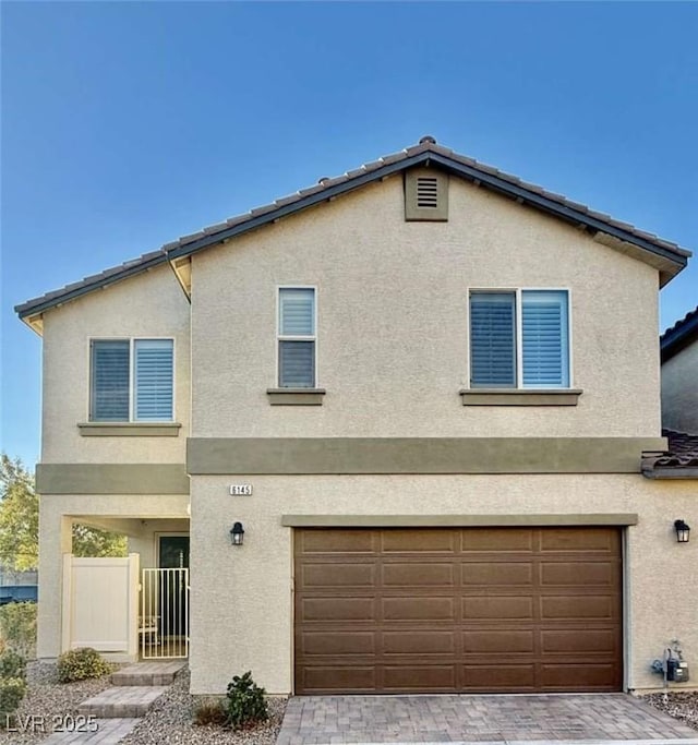 view of front facade featuring an attached garage, fence, and stucco siding