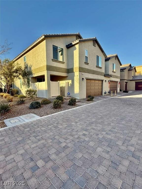 view of front of property featuring a tiled roof, decorative driveway, an attached garage, and stucco siding