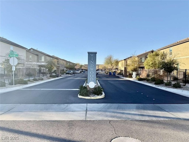 view of road featuring a gate, a residential view, a gated entry, and traffic signs