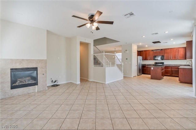 unfurnished living room featuring a fireplace, light tile patterned floors, recessed lighting, visible vents, and stairs