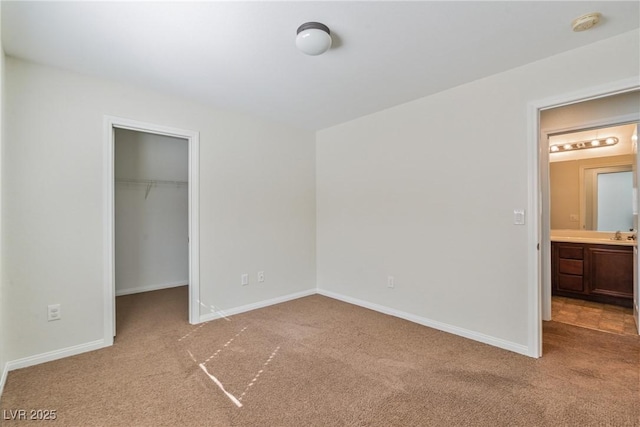 unfurnished bedroom with carpet, baseboards, a walk in closet, and a closet