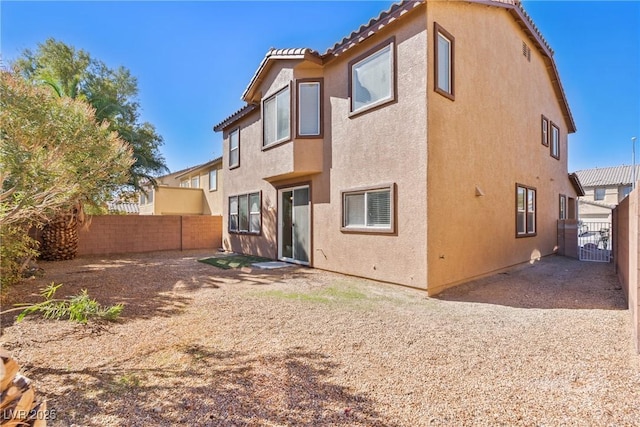 rear view of property featuring a fenced backyard, a tiled roof, and stucco siding