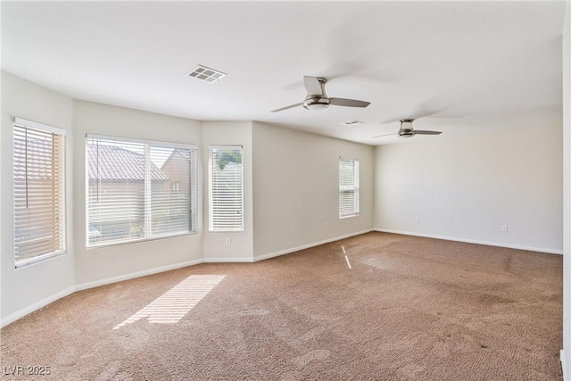 carpeted empty room with baseboards, visible vents, and a ceiling fan