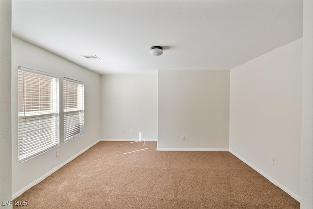 empty room featuring carpet floors, baseboards, and visible vents