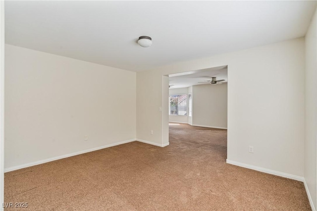 spare room featuring light carpet and baseboards