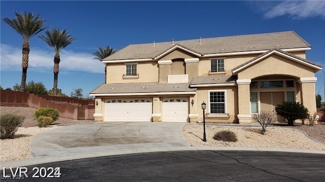 traditional-style home with fence, driveway, an attached garage, and stucco siding