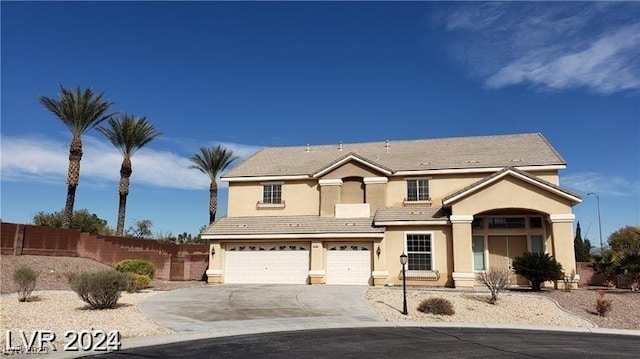 traditional home featuring a garage, driveway, a tiled roof, fence, and stucco siding