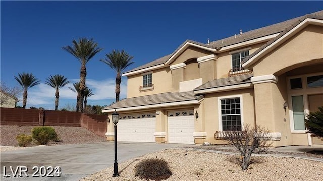 view of front of house featuring a garage, concrete driveway, fence, and stucco siding