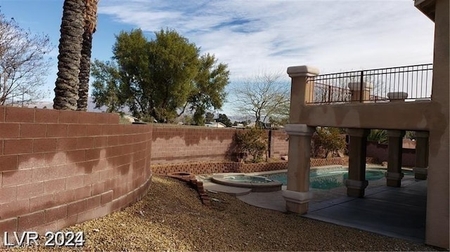 view of yard with a balcony, a fenced backyard, a pool with connected hot tub, and a patio