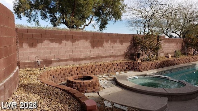 view of swimming pool featuring an outdoor fire pit, a pool with connected hot tub, and a fenced backyard