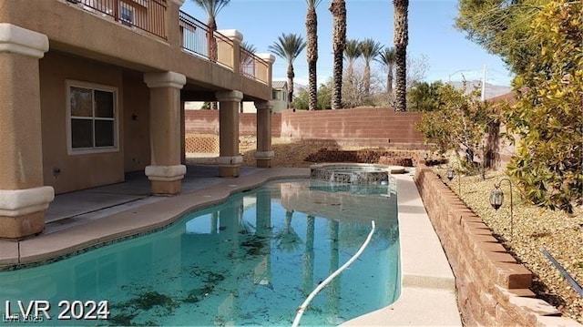 view of pool featuring fence and a pool with connected hot tub