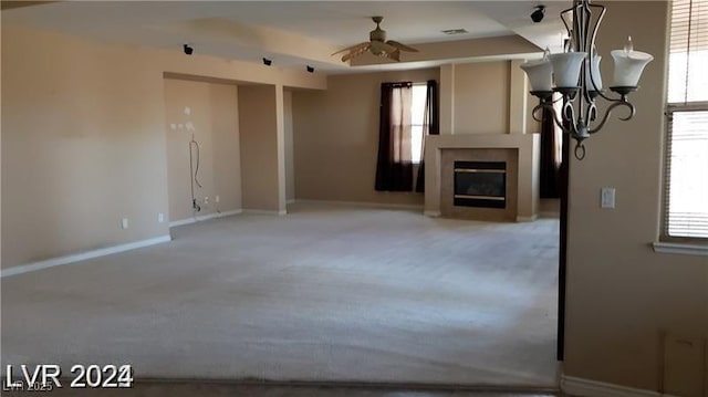 unfurnished living room featuring a fireplace, carpet flooring, a ceiling fan, baseboards, and a raised ceiling