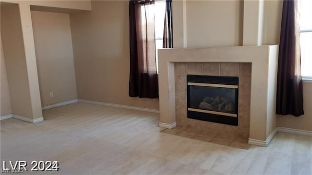 unfurnished living room featuring a tile fireplace and baseboards