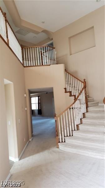 stairway with a towering ceiling and baseboards