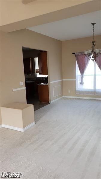 unfurnished living room featuring a notable chandelier and baseboards