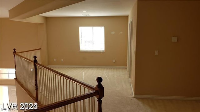 hallway with baseboards, light carpet, and an upstairs landing